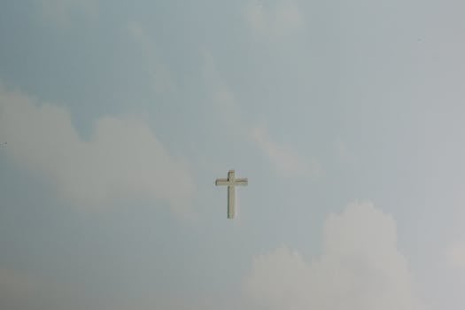 A solitary cross set against a softly clouded sky, symbolizing peace and spirituality.
